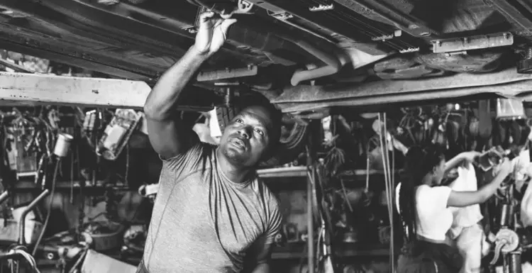 A mechanic works under a raised vehicle, Purolator