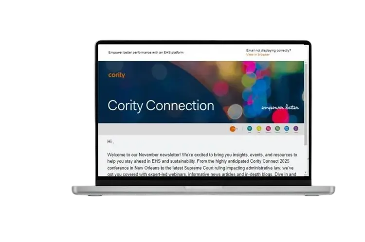 A laptop displaying the Cority Connection newsletter on its screen, featuring a dark blue header, colorful graphics, and a welcome message for the November edition.
